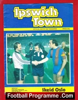 Cover of the Ipswich Town official match-day magazine; players shake hands on a football pitch amid a blue-red design with the 'Ipswich Town' header and 'Football Programme' label.
