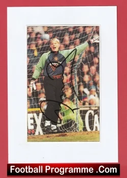 Soccer goalkeeper in green and black kit standing in front of the goal with arms raised, crowd in the stands behind; framed print with a red border and caption reading 'Football Programme .Com' at the bottom.