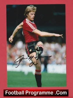 Footballer in a red kit mid-kick on a green pitch, autograph across the photo with a Football Programme.com border at the bottom.