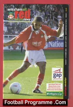 Football programme cover showing a male footballer in a red kit dribbling a ball on a grass pitch, with 'Football Programme.com' at the bottom and sponsor logos on the right side.