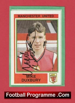 Signed Manchester United football programme card featuring Mike Duxbury with autograph, set against a red background.