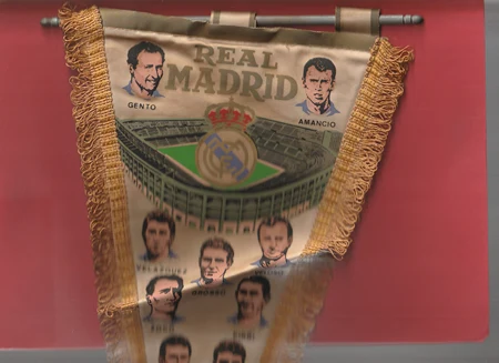 Real Madrid pennant with vintage player portraits and the club crest, hanging against a red backdrop.